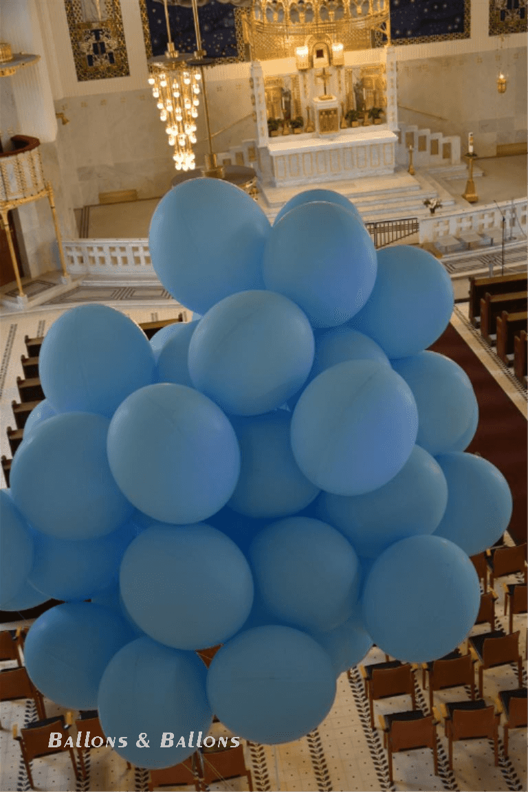 Eine Gruppe von blauen und weißen Ballons auf einem Kirchturm in Wien.