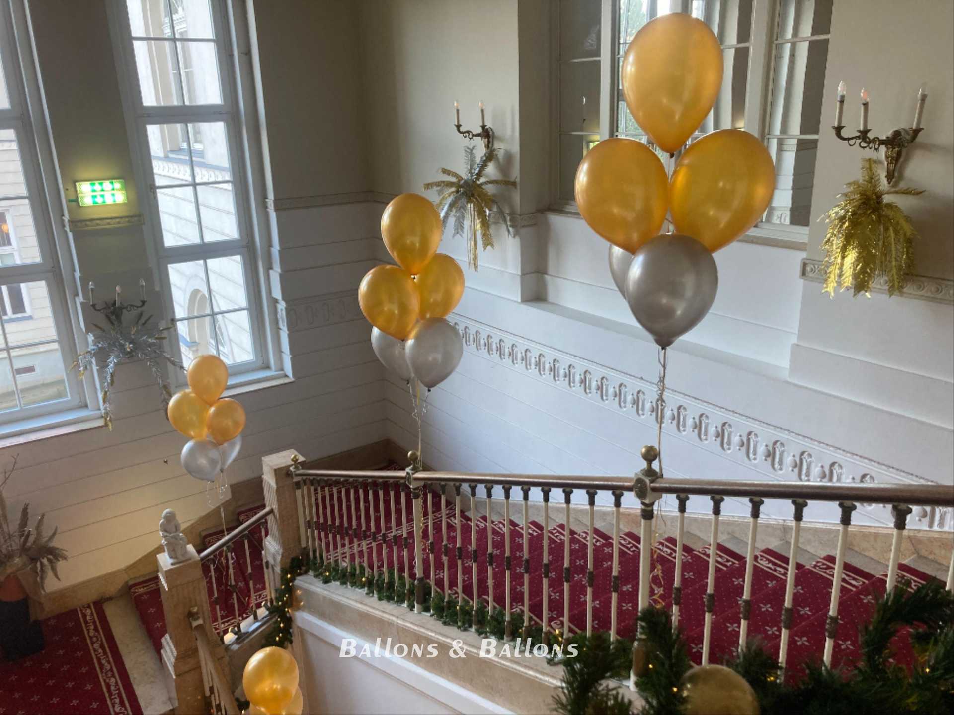 Viele goldene und silberne Ballons, die von einem Treppengeländer hängen, in Wien.