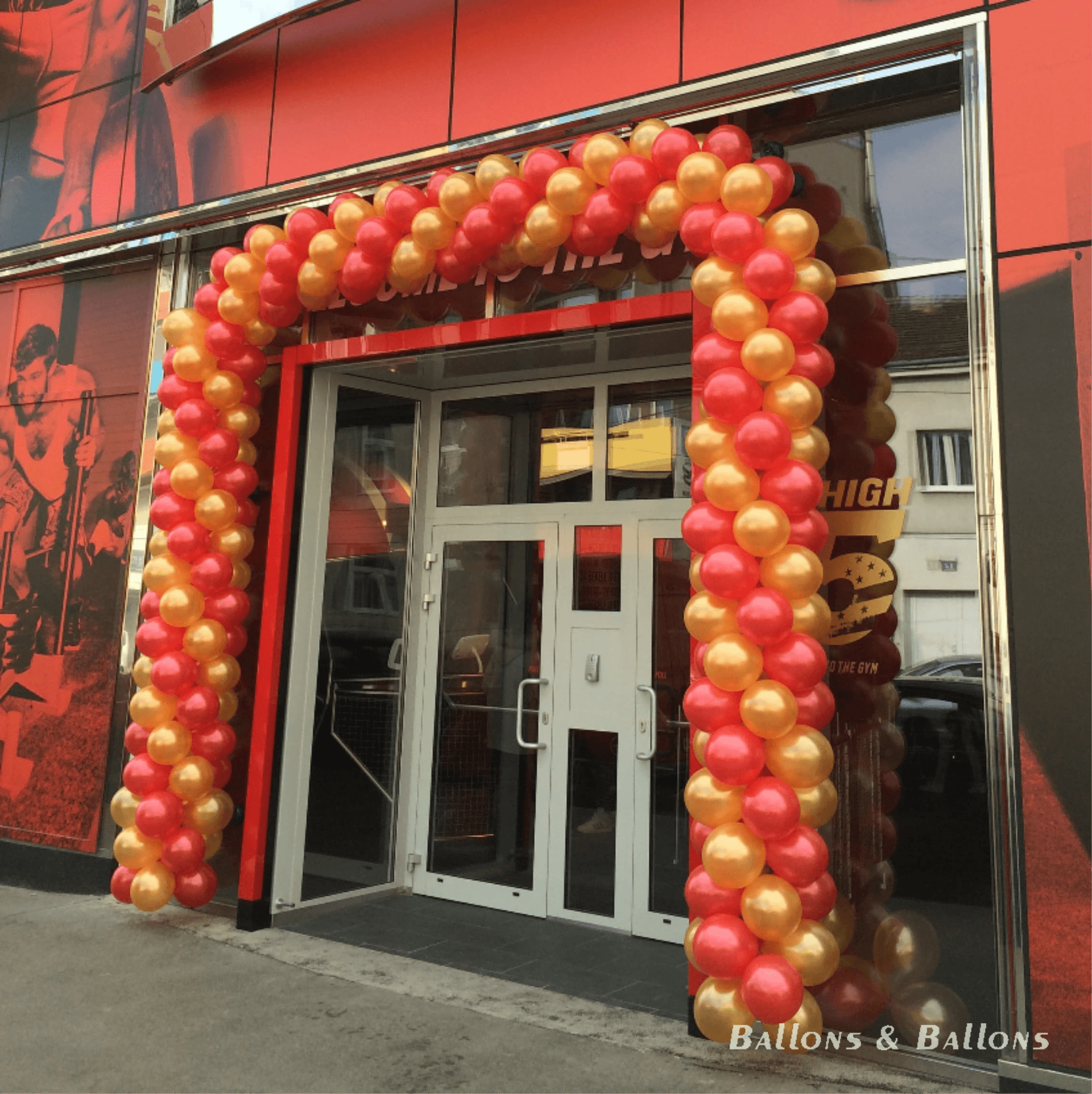 Eingang eines Gebäudes mit rotem und goldenem Ballonbogen in Wien