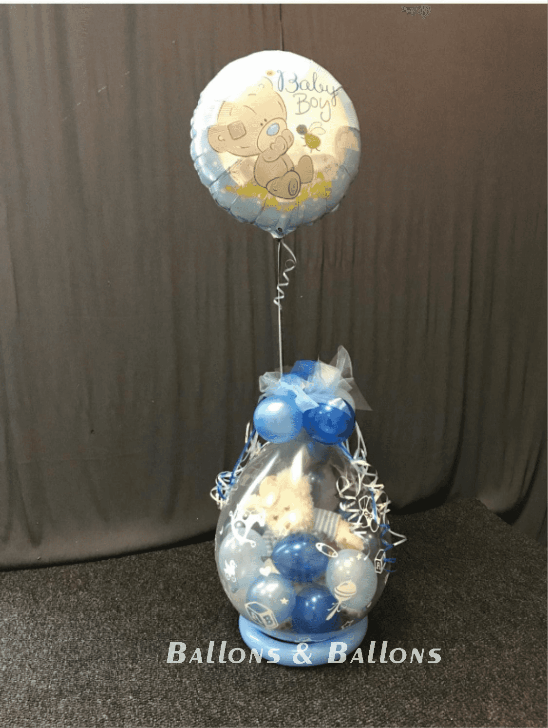 Ein Ballon in einer klaren Vase mit Tiermotiven, blaue Ballons und Ballons auf einem Tisch.