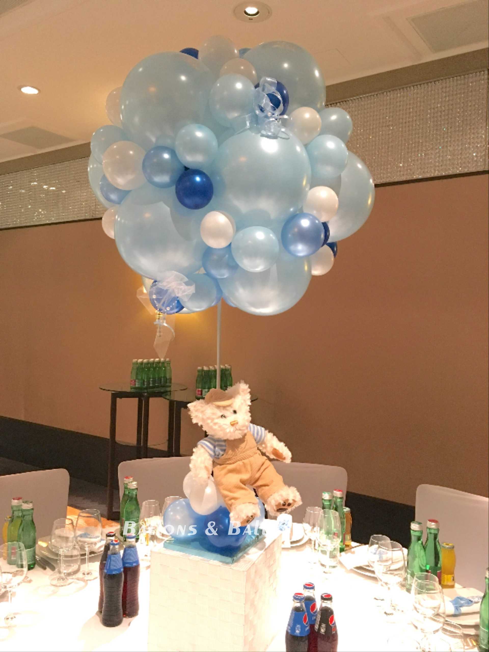 Ein Teddybär sitzt auf einer Ballontraube.