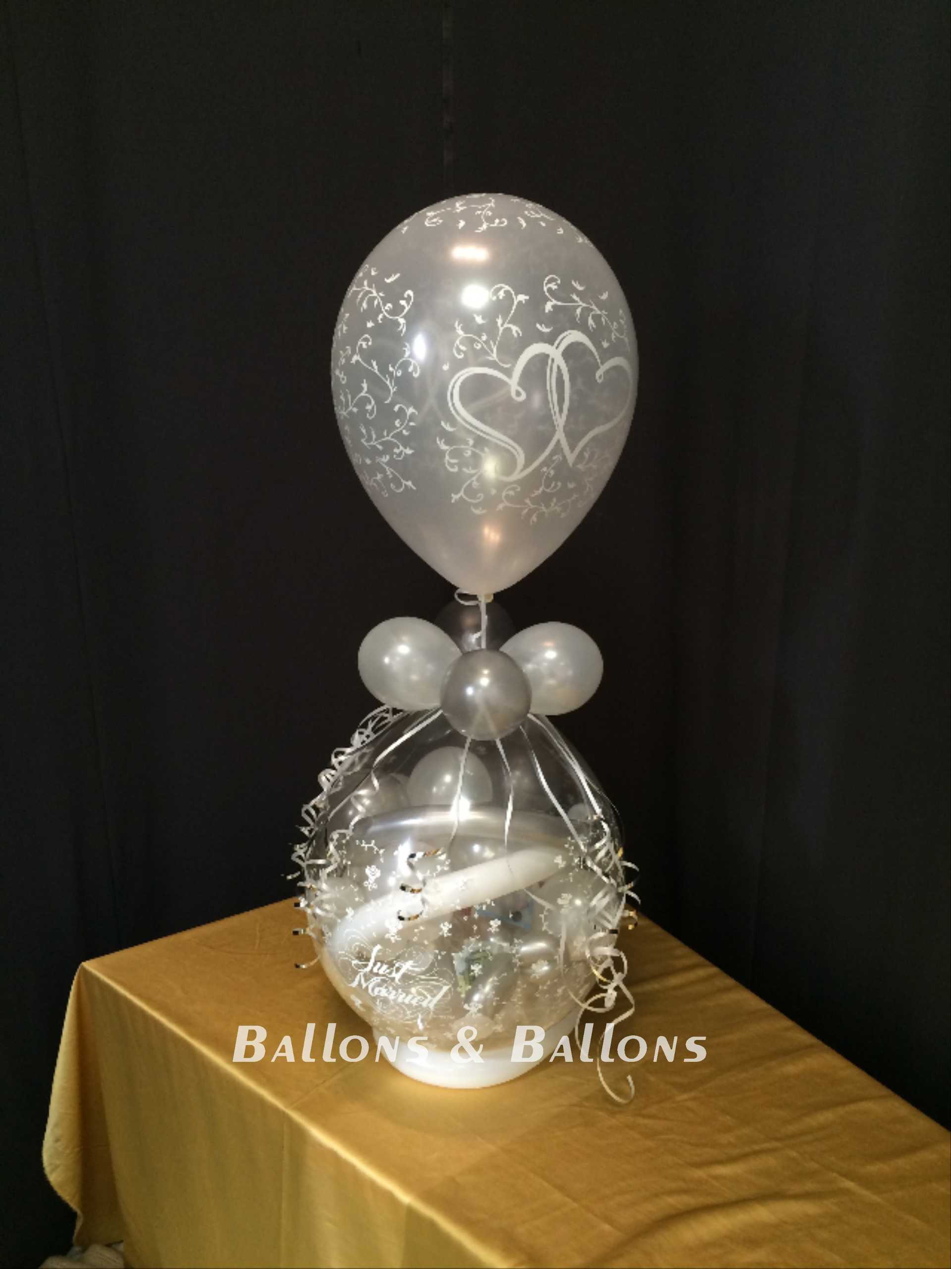 Ein weißer Ballon mit zwei silbernen Ballons, bunte Ballondeko.