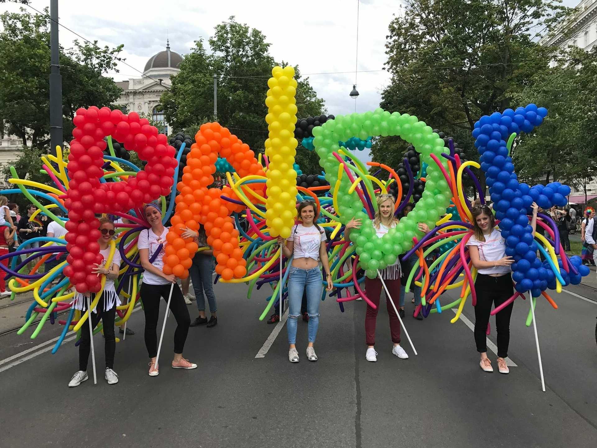 Eine Gruppe von Menschen mit Ballons mit der Aufschrift "Pride" in Wien.