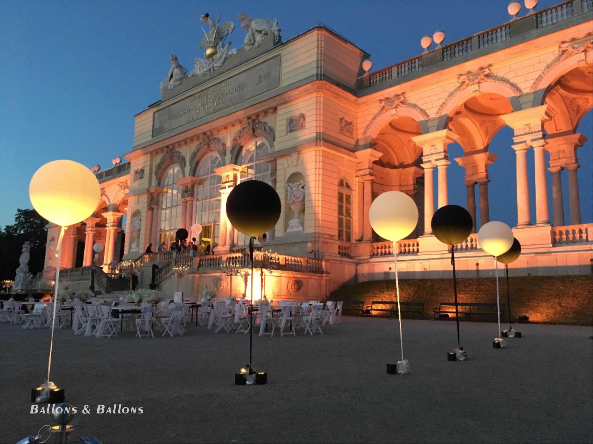 Mehrere runde Tische mit schwarzen und weißen Ballons in Wien.