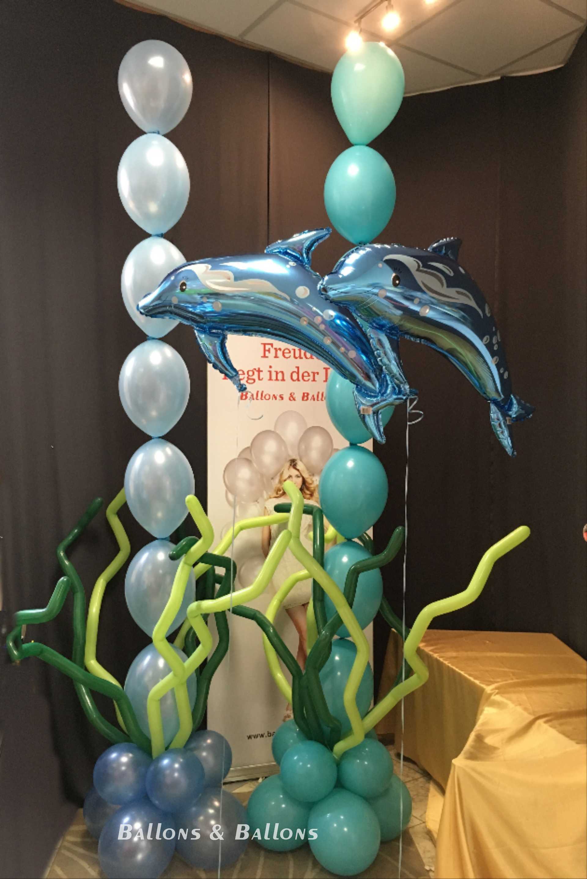 Drei blaue Ballons mit Delfinen und einer blauen Pflanze in Wien.