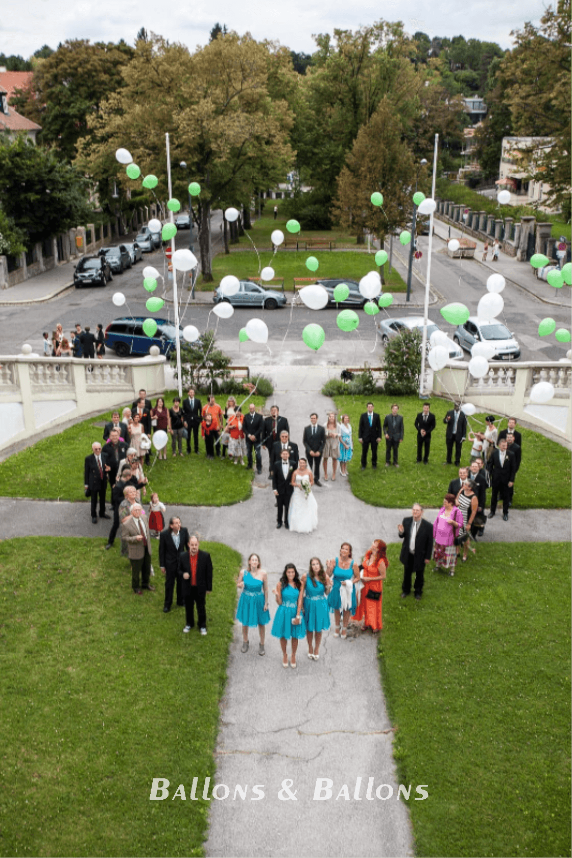 Eine Gruppe von Menschen hält Ballons über einer Hochzeitsgesellschaft.